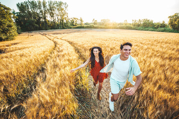 Young romantic couple of lovers running in a wheat field - Happy boyfriend and girlfriends having...