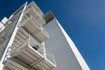 modern white concrete building with external metal fire escape stairs