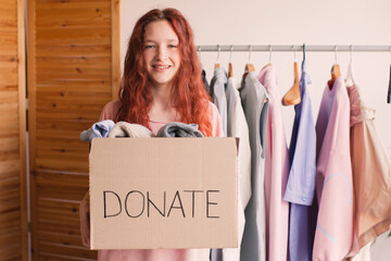 Smiling young woman putting clothing into donation box - 758794573