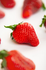 Close-up of strawberry on white background and surrounded by other strawberries out of focus.