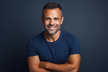 Portrait of a handsome man smiling at the camera with his arms crossed - obrazy, fototapety, plakaty