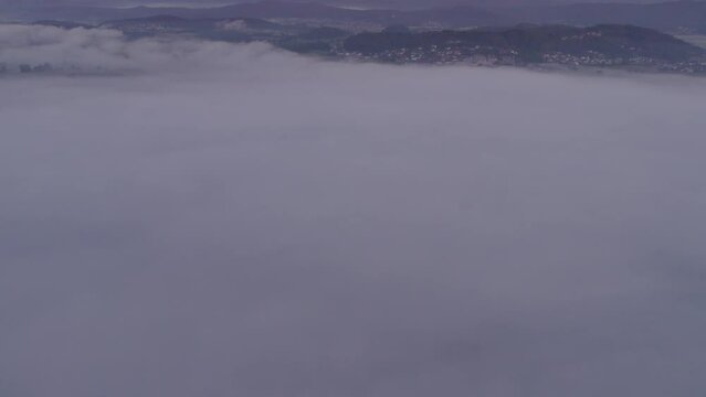Aerial view of St. Anne's Church (Cerkev sv. Ane) on top of a mountain with low fog, Jezero, Slovenia