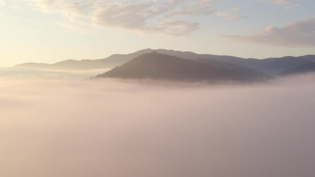 Aerial view of St. Anne's Church (Cerkev sv. Ane) on top of a mountain with low fog, Jezero, Slovenia