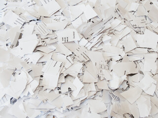 Closeup of printed pay or salary paper documents in a pile, which have been cut and torn or...