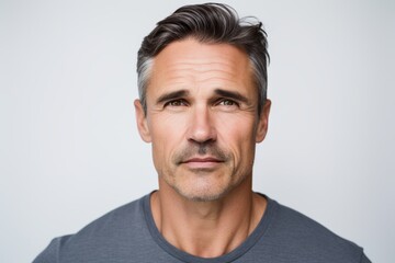 Portrait of handsome mature man in grey t-shirt, isolated on grey background