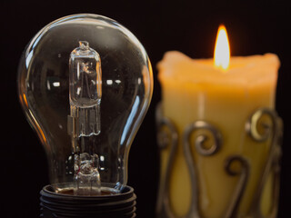 Closeup, isolated shot of a sharply focused unlit electric lightbulb, next to a defocused burning...