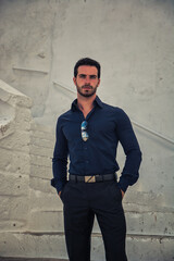 Obraz premium A man is standing upright in front of a plain white wall, his hands by his sides. He appears to be looking straight ahead with a neutral expression.