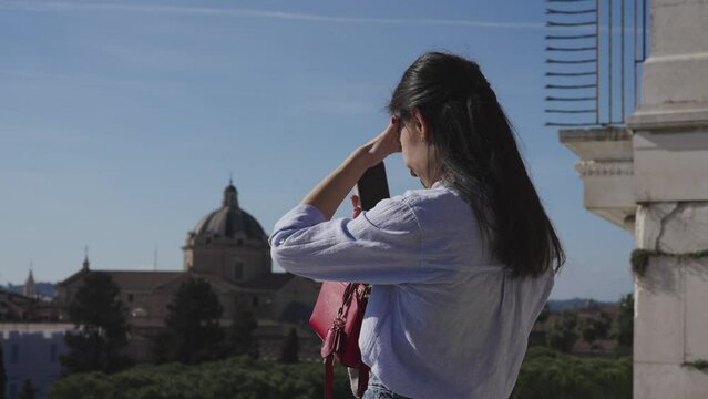 Young beautiful tourist woman using a mobile phone checking directions on visit of ancient Rome, Italy