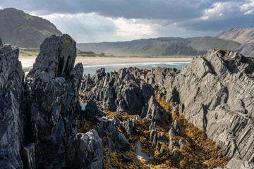 Rock formations in Sandfjorden beach by the Barents Sea near the town of Berlevåg on a sunny...