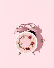 Vintage alarm clock, creative clock face, romantic floral pattern, pastel pink background.