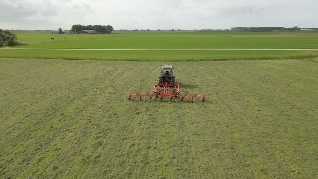 Aerial view of tractor turns the grass with a hay rake attached, Friesland, Netherlands