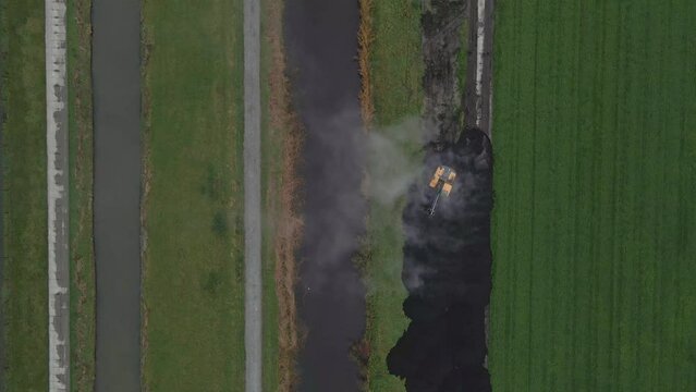 Aerial view of crane and truck that unloading mud in grassland