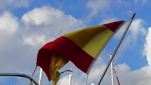 spanish royal flag on mast of sailing ship in marina