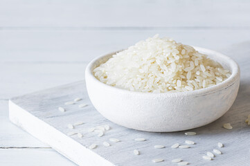 turkish raw white rice grains in bowl or spoon on table, healthy food uncooked legumes concept