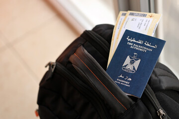 Blue Palestinian Authority passport with airline tickets on touristic backpack close up. Tourism and travel concept