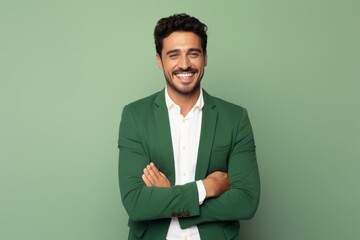 Portrait of a happy young man standing with arms crossed isolated over green background