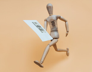 A wooden mannequin runs with an envelope with money. Concept for delivery, money transfer, lottery...