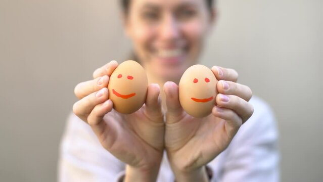 In the girl’s hands are eggs with painted emotions. The girl holds eggs with emoticons in front of her