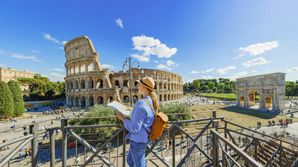  Happy woman tourist looking up from map at Rome Colosseum