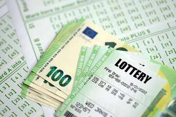 Green lottery tickets and euro money bills on blank with numbers for playing lottery close up