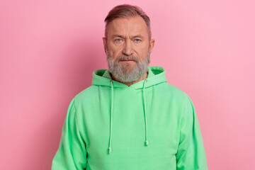 Photo of serious confident man wear green sweatshirt looking you isolated pink color background