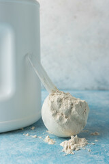 Whey protein powder in measuring spoon on a blue background