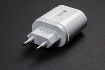 Usb charger. White euro plug, new smartphone AC power charging plug on dark background