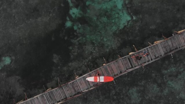 Aerial view of surfer walks on wooden walkway to cross the reef, Cloud9, Siargao, Philippines