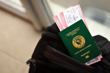 Green Nigerian passport with airline tickets on touristic backpack close up. Tourism and travel concept