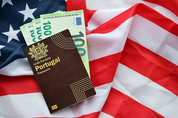 Red Portugal passport of European Union and money on United States national flag background close...