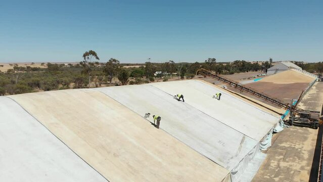 Aerial view of workers sealing the stitches from grain storage, Geraldton, Australia