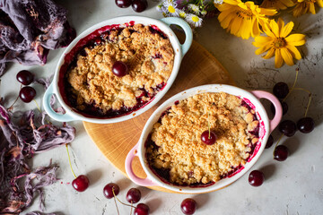 Dessert for breakfast for the whole family: cherry crumble in beautiful shapes on a gray background. Close-up