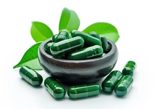Herbal medicine capsules with fresh green leaves isolated on white background. Spiruline isolated white
