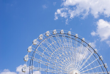 Ferris wheel in white color against summer blue sky