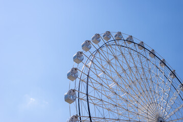 Ferris wheel in white color against summer blue sky