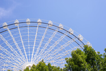 Part of ferris wheel in white color against summer blue sky