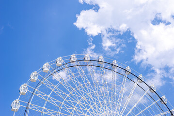 Top of ferris wheel in white color against summer blue sky - with large copy space