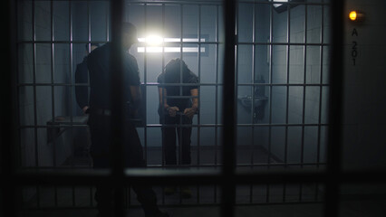 Warden brings new prisoner in jail cell and takes off his handcuffs. African American teenager...