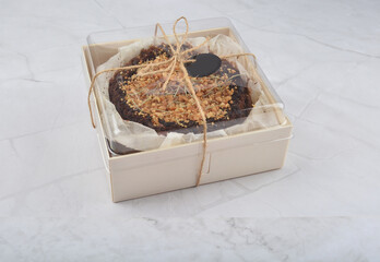 premium freshly baked dark cocoa chocolate brownie gold flower and earl grey peanut round birthday cake with walnut in wood bento box on white marble halal food sweet dessert menu for pastry cafe shop