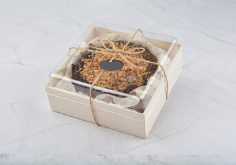 premium freshly baked dark cocoa chocolate brownie gold flower and earl grey peanut round birthday cake with walnut in wood bento box on white marble halal food sweet dessert menu for pastry cafe shop