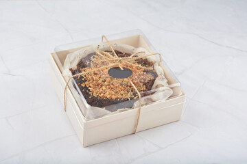 premium freshly baked dark cocoa chocolate brownie gold flower and earl grey peanut round birthday cake with walnut in wood bento box on white marble halal food sweet dessert menu for pastry cafe shop