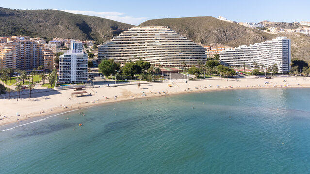 Large apartment buildings on the coast of Cullera in the province of Valencia (Spain) and its beach on a sunny day with the mountain behind them.