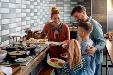 Happy family enjoying in buffet breakfast in hotel.