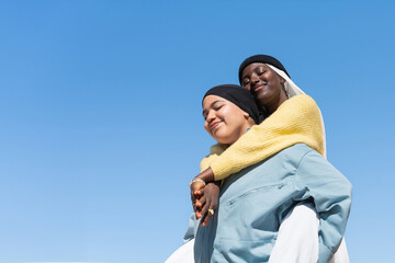 Two Gen Z young muslim women friends embracing with love and friendship