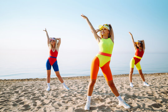 Beautiful women are dancing on the beach. Fitness, training, aerobics and people concept. Active sport.