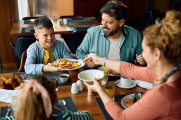 Happy boy enjoying in breakfast with his family in  hotel restaurant.