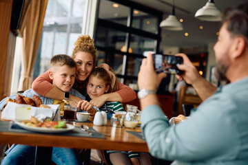 Happy family taking picture while having  breakfast in  restaurant.