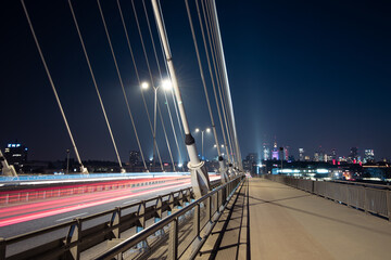 Obraz premium Light trails on a road and a city skyline 