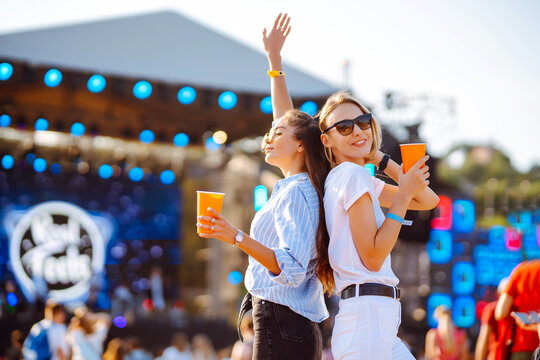 Two young woman with beer at beach party. Music festival. Summer holiday, vacation concept.