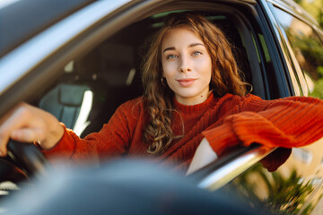 Portrait of young woman is driving a car and smiling. Car travel, lifestyle concept.